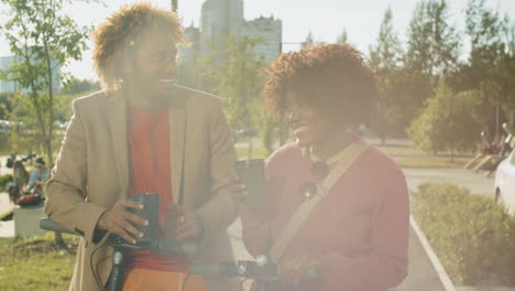 Afroamerikanische-Freunde-Mit-E-Scootern-Und-Kaffee-Im-Park