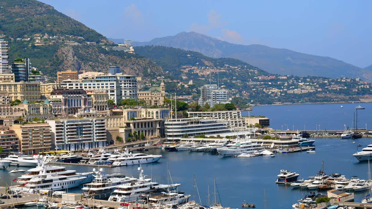 Aerial view of white boats docked in the Monaco Marina with the skyline on the background