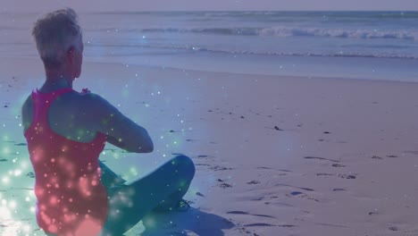 animación de puntos de luz sobre una mujer caucásica practicando yoga y meditando en la playa
