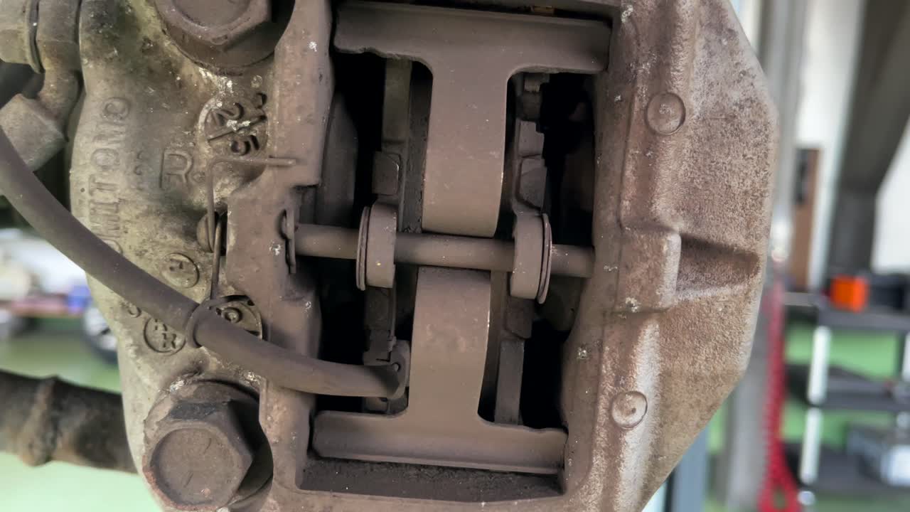 렉서스 ls 430 후면에 있는 마모된 브레이크 캘리퍼와 브레이크 패드의 측면 샷을 닫습니다.