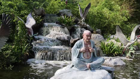 statue meditates by a cascading waterfall