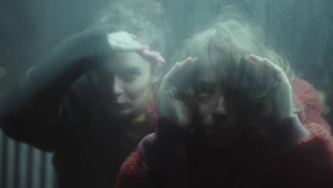 two young women staring at camera through glass