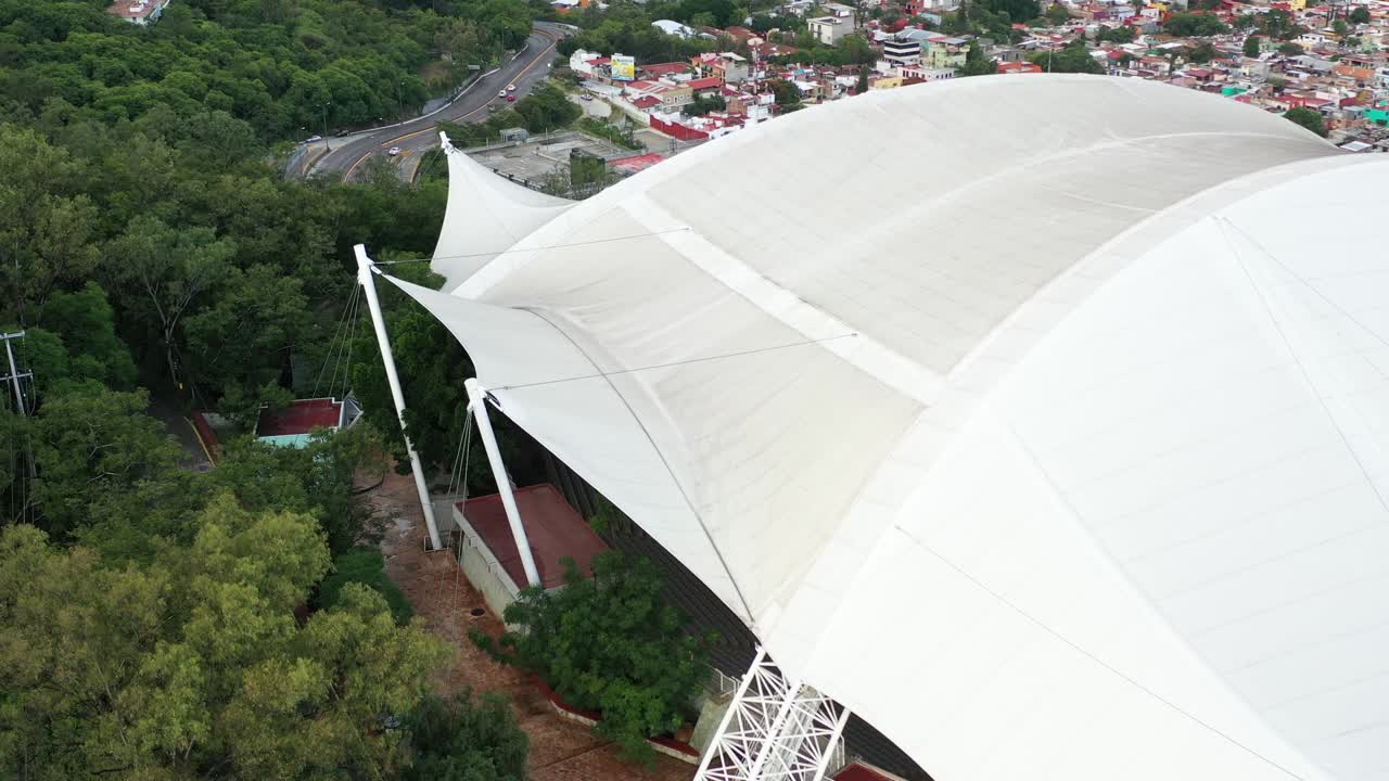 Slow aerial revealing shot of a small covered stadium on the outskirts of Mexico