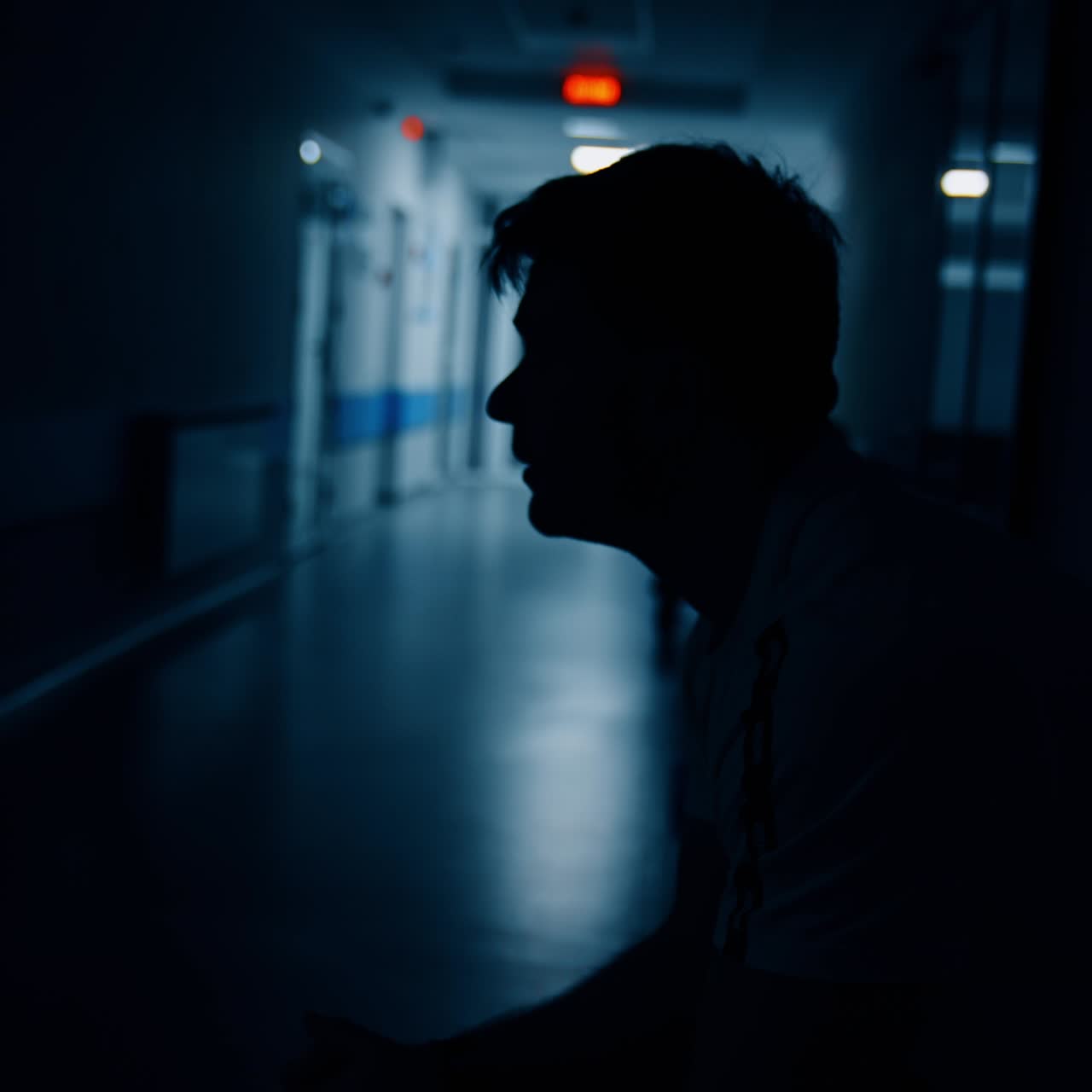Nervous man sits in the corridor of maternity hospital. Worried husband waiting for the good news about his newborn baby. Dark hall backdrop