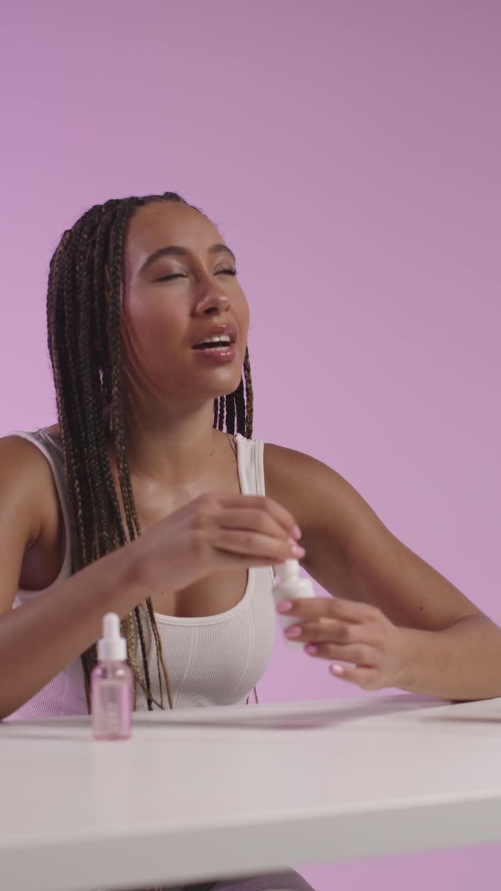 mujer joven grabando belleza maquillaje revisión o tutorial para suero de cuidado de la piel en teléfono móvil para cargar en las redes sociales canal 4