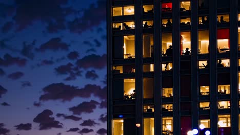 people at windows in a city building at night