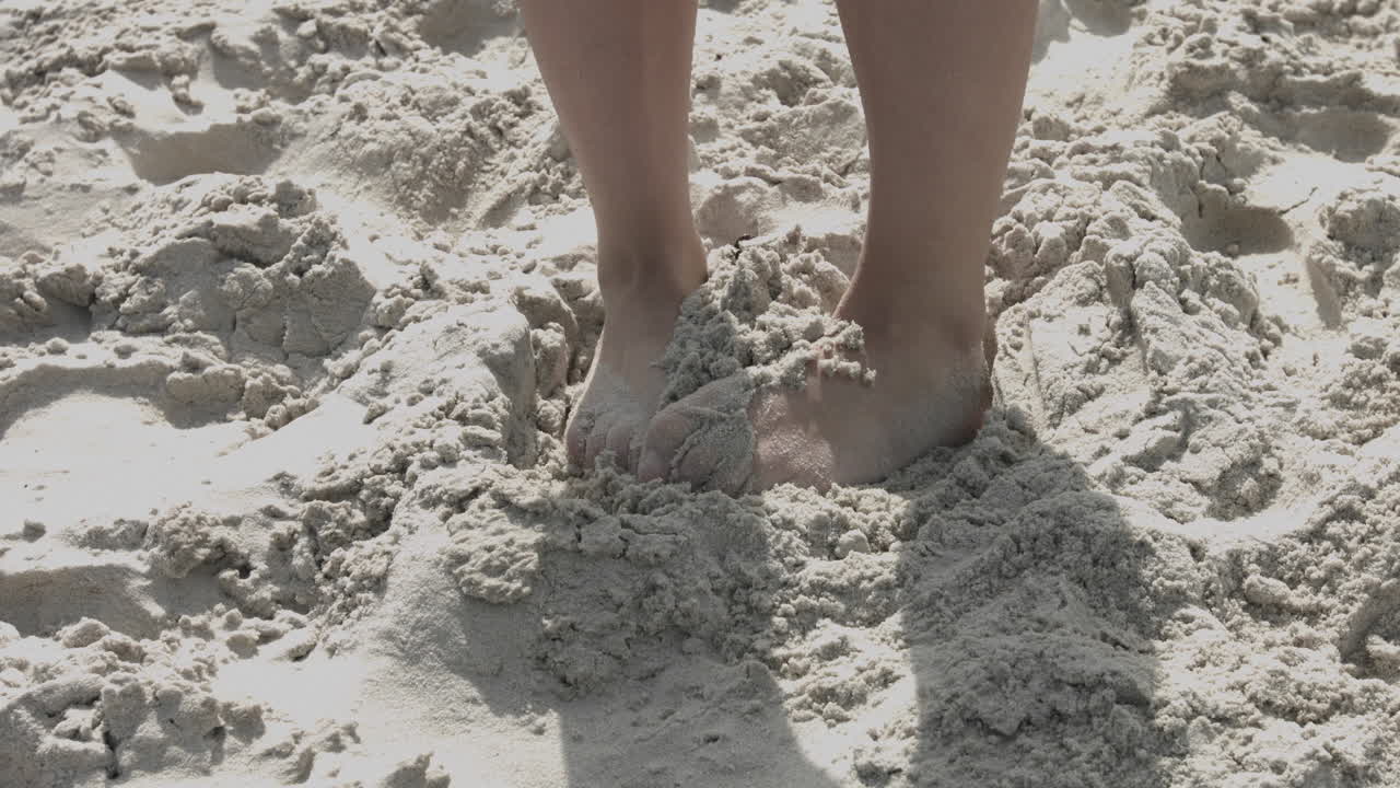 Ashamed woman hides her feet in the sand. Close-up on a woman's leg with problems on her toes