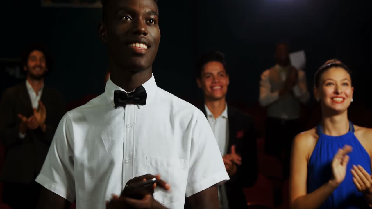 Grupo de pessoas aplaudindo enquanto assiste a um filme 4k