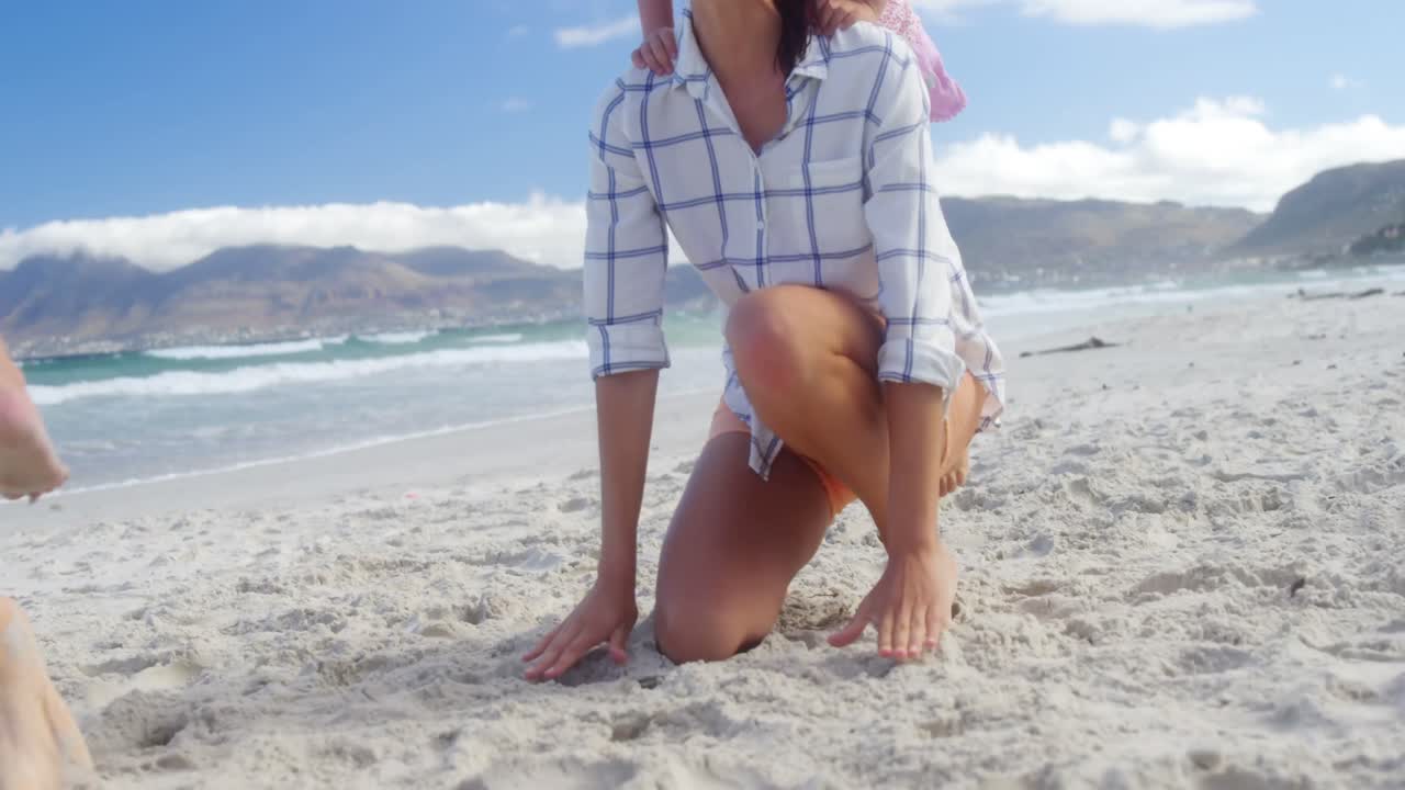 madre dando paseo a cuestas a su hija en la playa