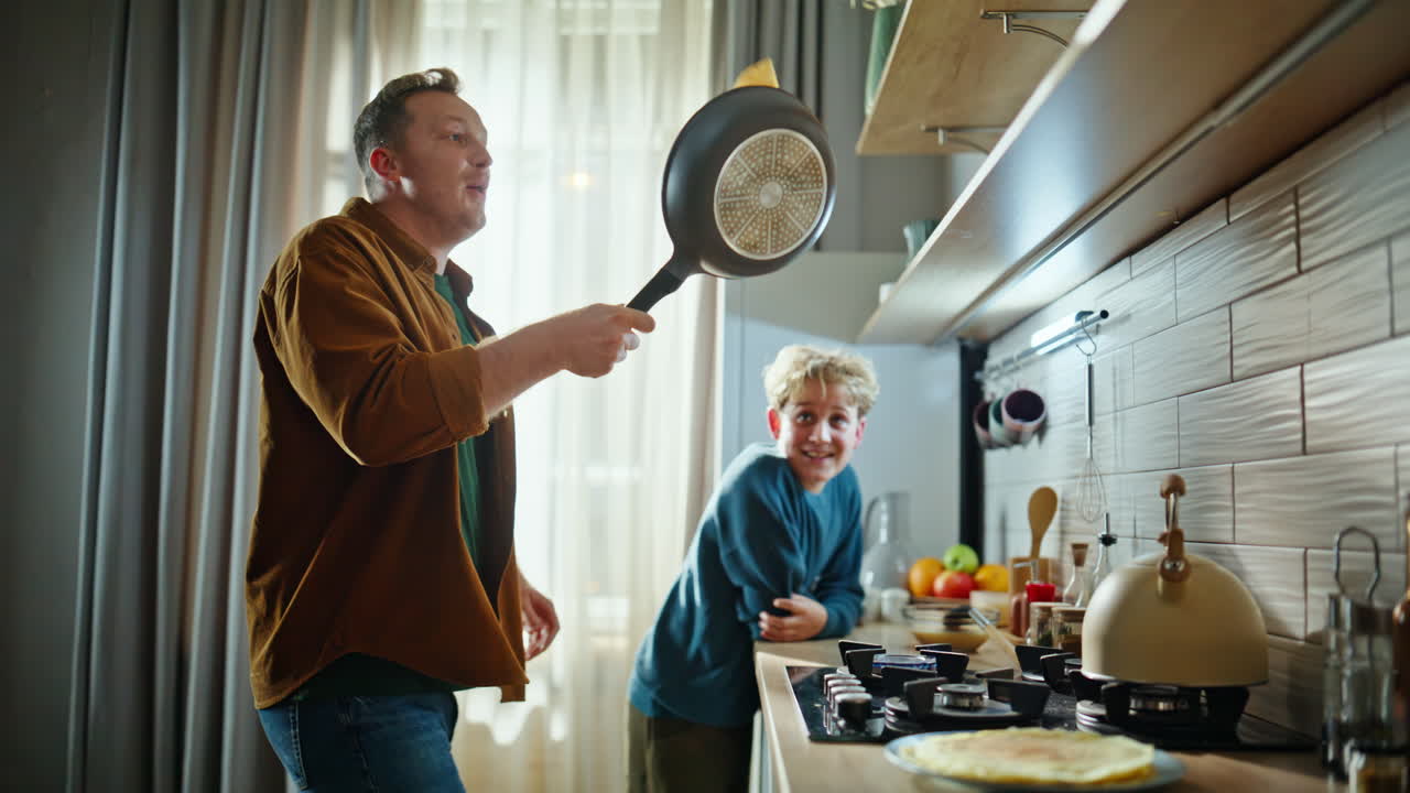 Vater und Kind bereiten gemeinsam Pfannkuchen zu, genießen einen gemütlichen Morgen zu Hause, Nahaufnahme.