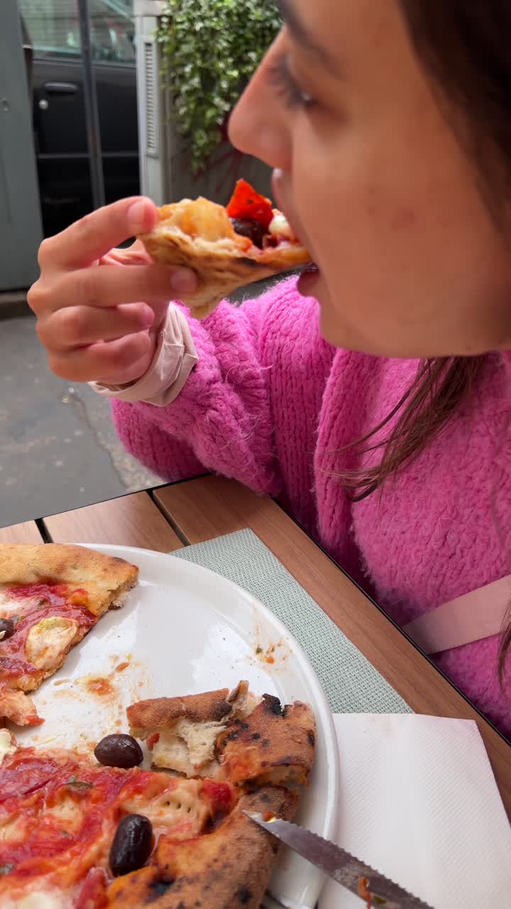 Persona comiendo un trozo de deliciosa pizza italiana al aire libre