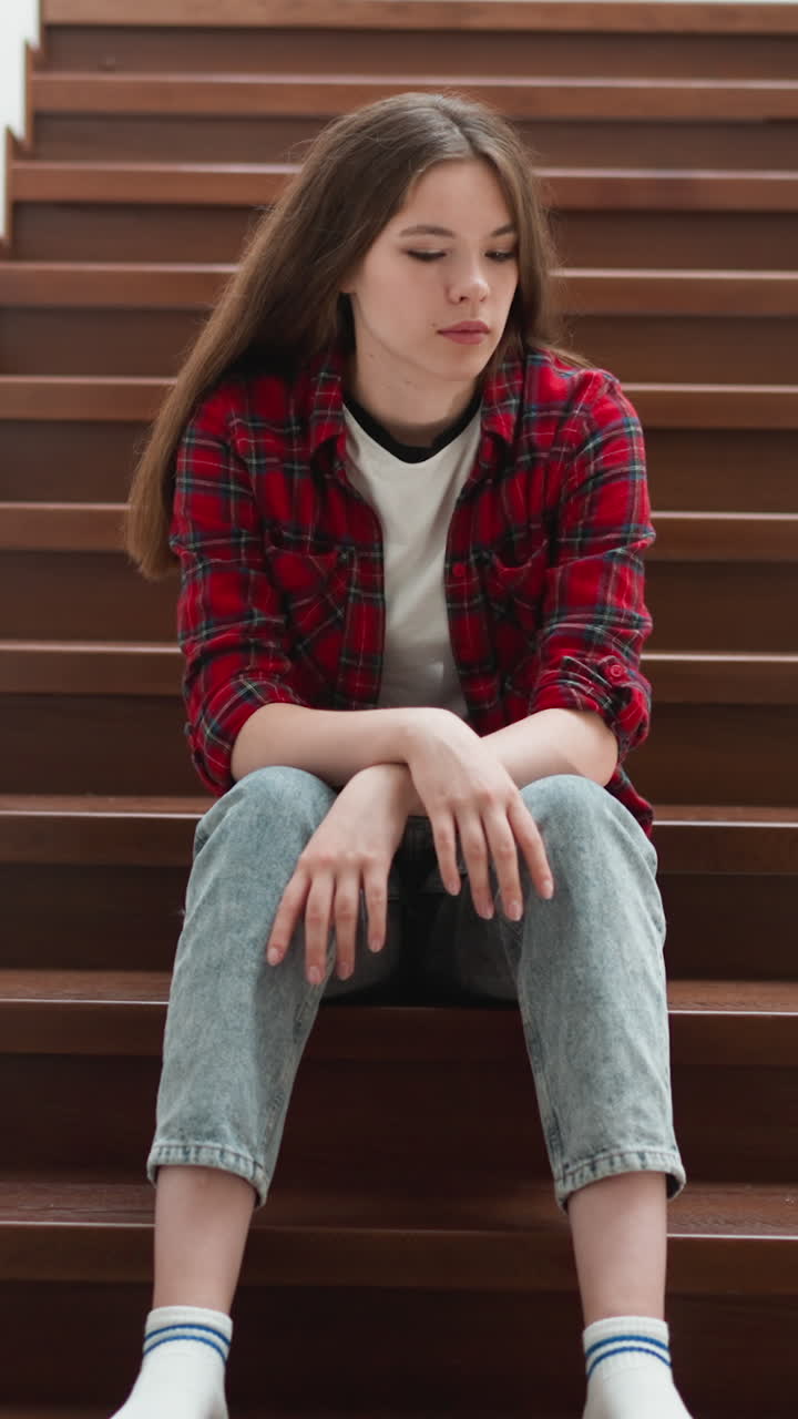 Young woman with pensive expression sits on stairs. Adult daughter sorrows about terrible quarrel with parents at home. Emotional problems overcoming