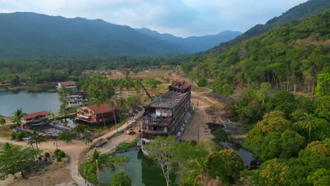 Abandoned resort showing decaying buildings, surrounded by palm trees and a lake, in Koh Chang, Thailand. Fabulous aerial view flight circle drone footage