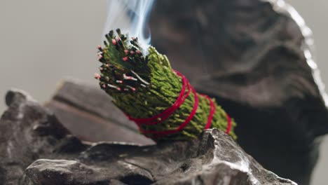 person holding palo santo wood stick in hand, aromatic palo santo burning on black background, smoke spreading around, slow motion video clip, high quality 4k close up footage. high quality 4k footage