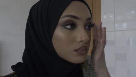 young muslim woman checking makeup whilst looking in mirror