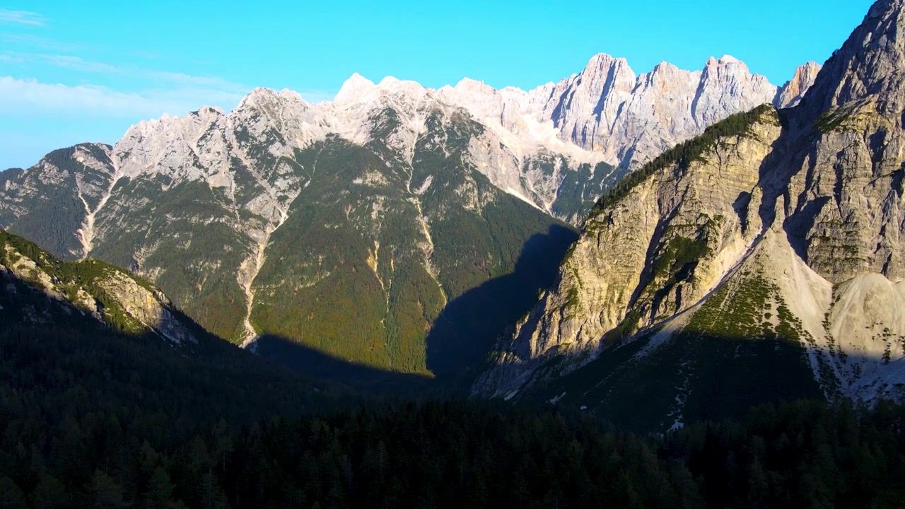 Pemandangan udara puncak Pegunungan Alpen Julian yang dramatis menjulang di atas lembah gunung berhutan, Slovenia.