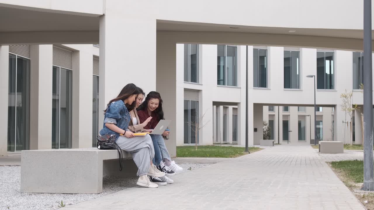 three asian girl students using the laptop at break time sitting on campus