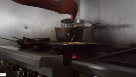 Chef-sprinkles-onion-in-a-frying-pan-with-shrimp-in-the-kitchen