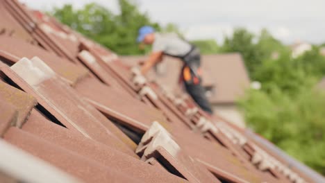 Person-working-on-roof,-removing-tiles-for-solar-panel-installation