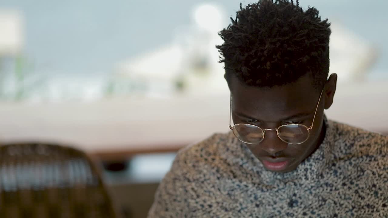 Focused young man in eyeglasses working in coffee shop
