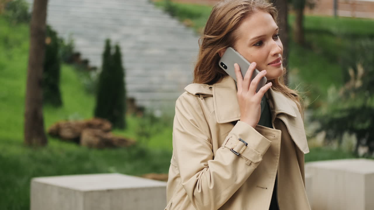 Caucasian female student talking on the phone outdoors.