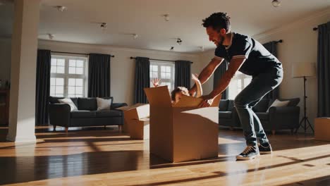 father and son playful interaction with cardboard box in living room