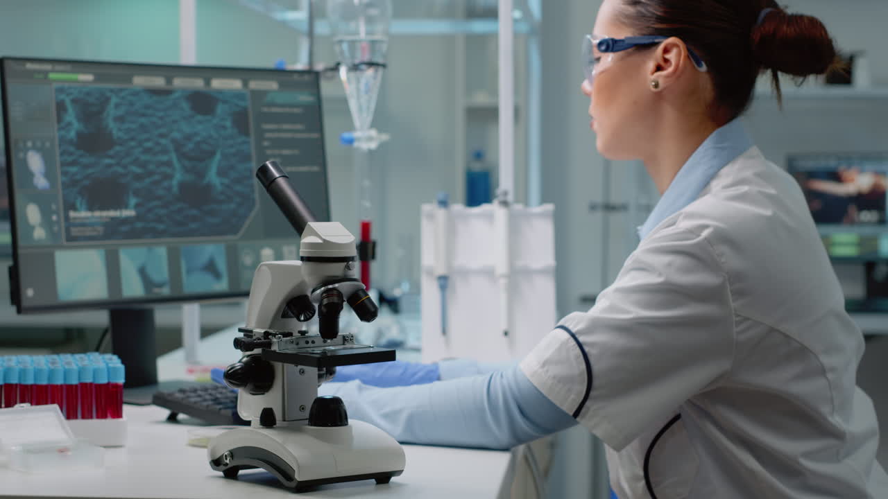 Scientist Working in Laboratory with Microscope and Blood Samples