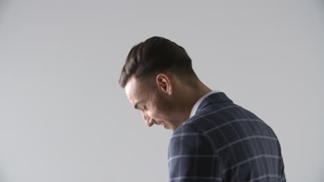 young man in suit turns, looks down, tugs lapels, close up