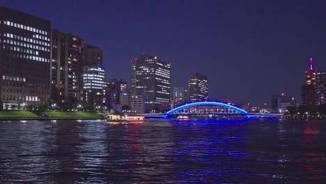 Night-light-Tokyo,-Tsukuda,-Toyosu-skyscrapers-and-Kiyosu-bridge-the-Sumida-River-Yakatabune,-pleasure-boat