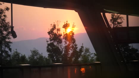 vista del atardecer detrás de los árboles desde la ventana del tren en
