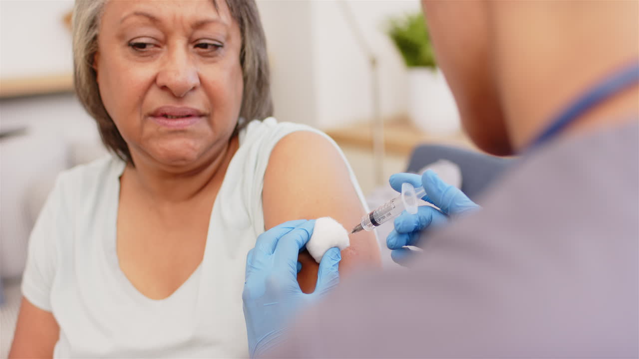 Administering vaccine, healthcare worker giving injection to senior woman in clinic