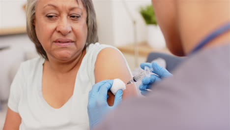 administering vaccine, healthcare worker giving injection to senior woman in clinic