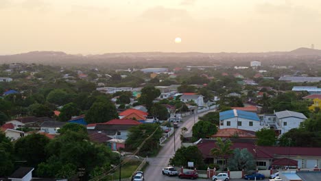 sun sets behind hazey clouds on quiet edge of caribbean neighborhood