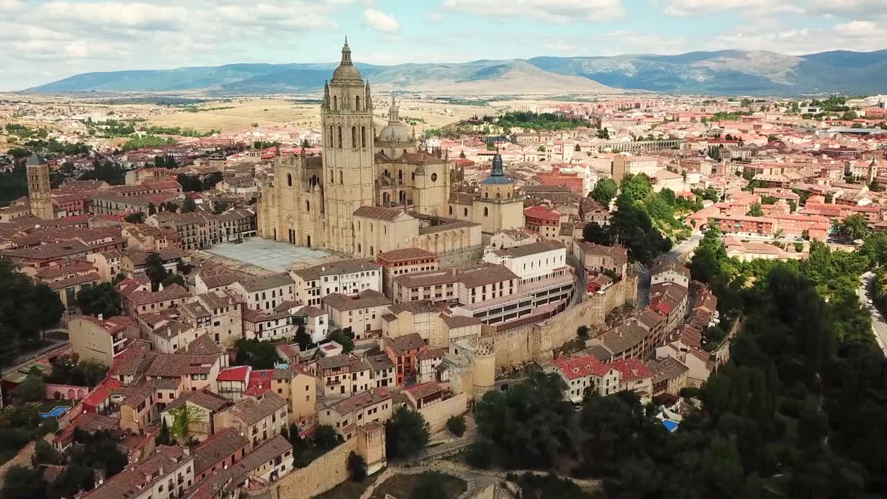 Aerial view of the historic cathedral and surrounding old town of Segovia, Spain, highlighting its stunning architecture, medieval charm, and picturesque landscapes framed by rolling hills