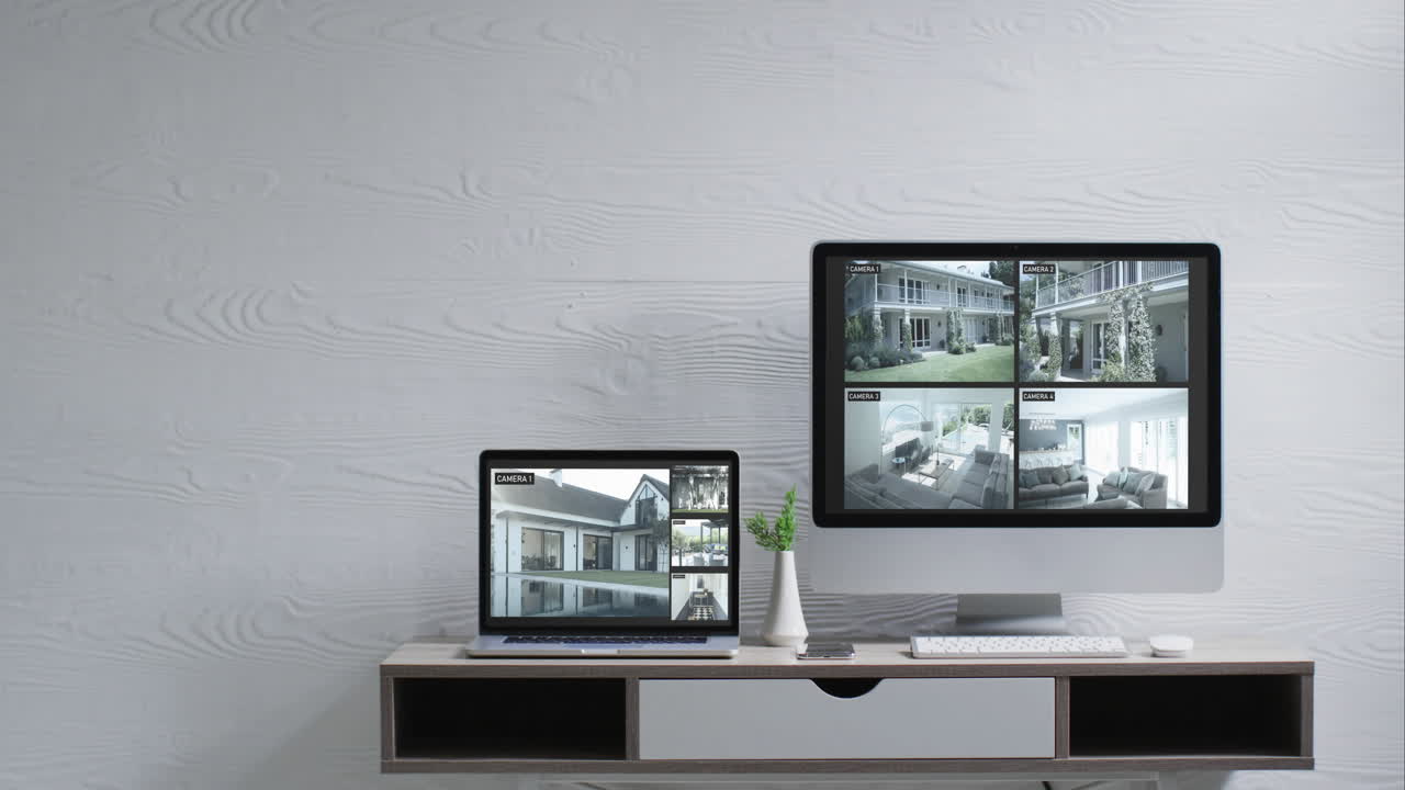 벽에 장착된 컴퓨터 모니터와 책상 위의 노트북과 스크린에 있는 보안 카메라 뷰, 느린 동작