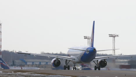 a back view of a plane moving on an airport courtyard