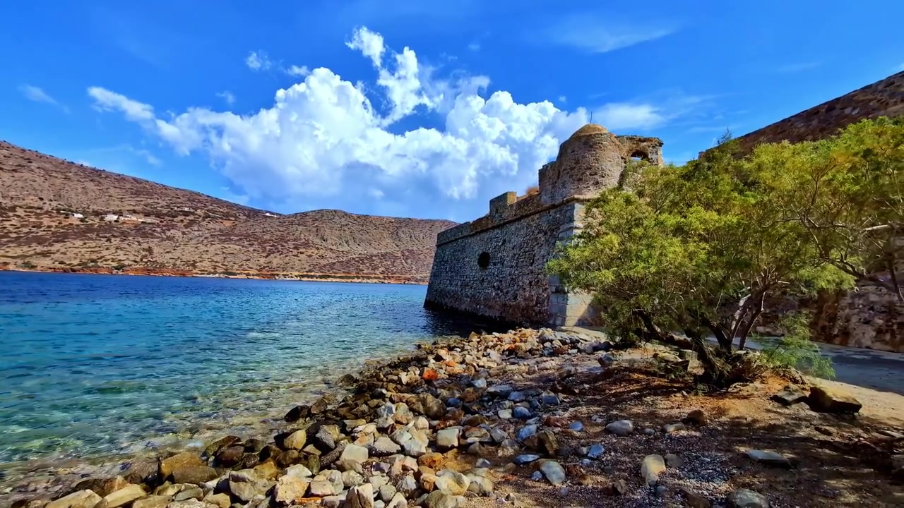 Fortezza storica su una costa rocciosa con mare blu e cielo luminoso, vista paesaggistica.