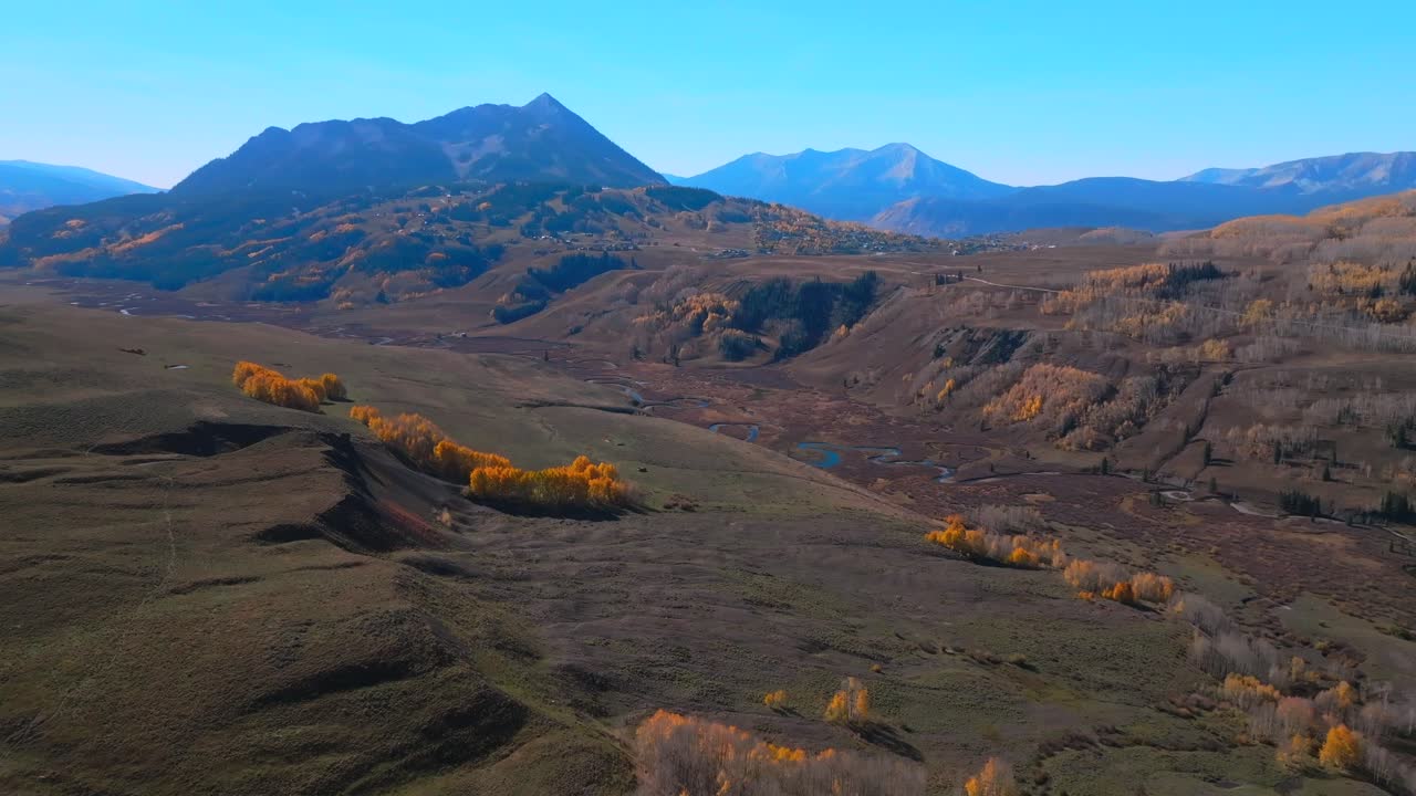 Mount Crested Butte Gothic mountain town ski resort vibrant aspen trees fall autumn peak colors aerial drone Colorado morning Kebler Pass Gunnison National forest morning bluesky forward pan up motion
