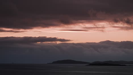 the soft glow of a setting sun casts a warm light over the horizon, with islands silhouetted in the distance