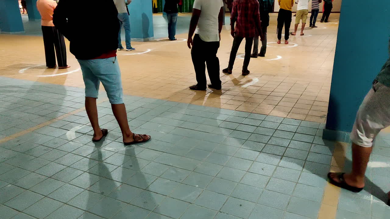People Queuing Inside Marked Circles at a safe distance in the Underground Parking Lot of Supermarket to purchase essential goods during Coronavirus Pandemic Lockdown