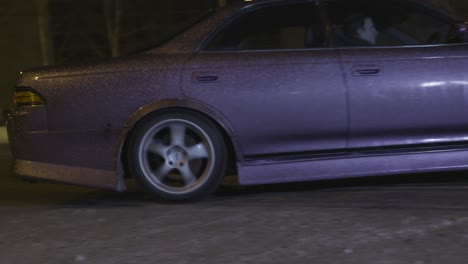 purple sedan drifting on snowy road at night