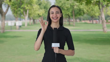 happy indian female news reporter showing okay sign