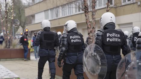 police officers in riot gear slowly approaching a group of protesters, slow motion