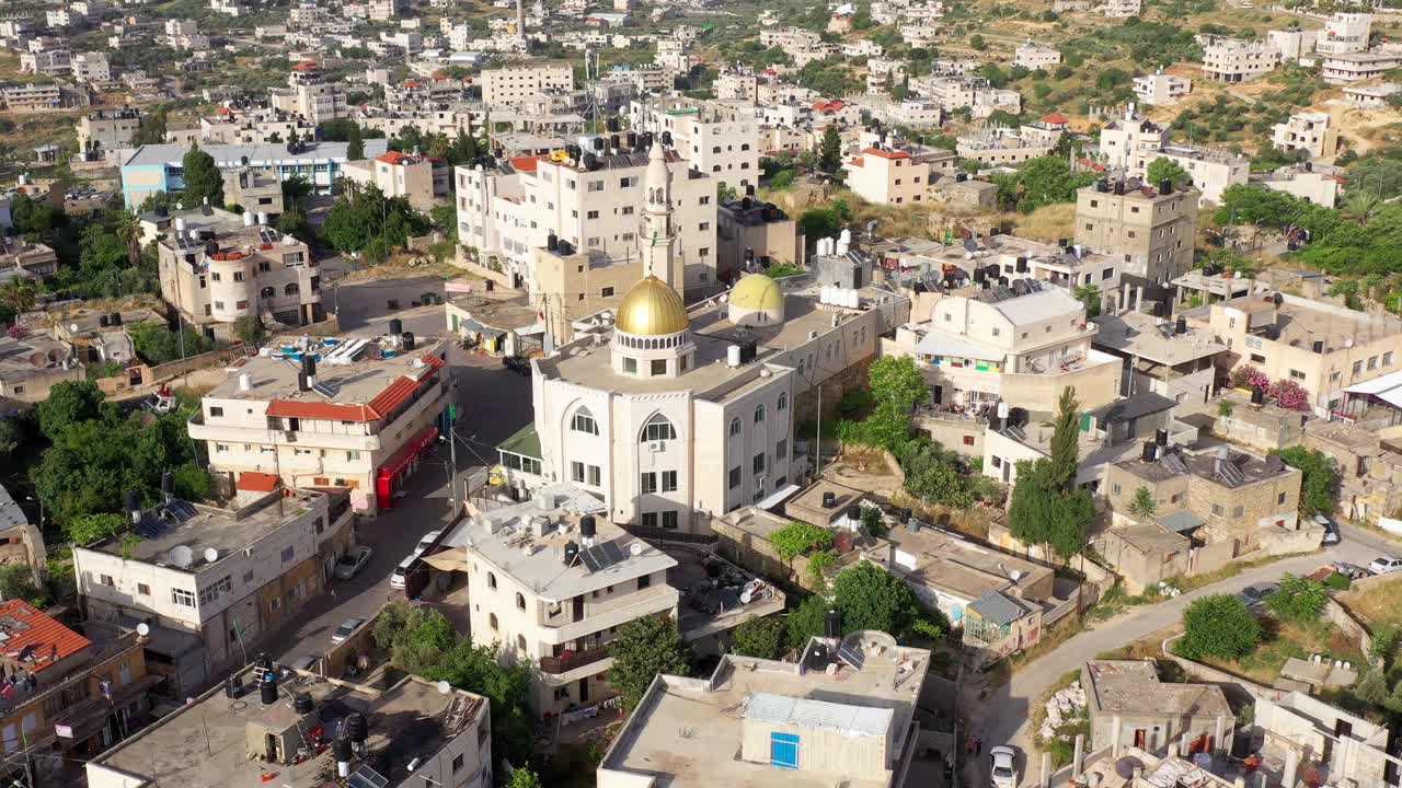 Aerial view of a Middle Eastern town with a prominent mosque featuring a golden dome and minaret