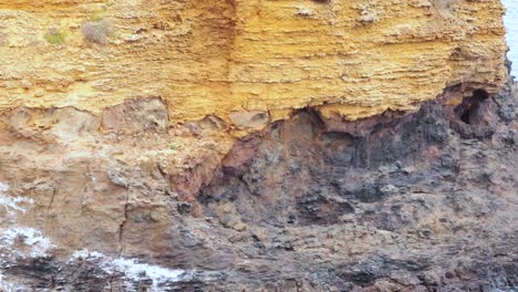 las olas del océano golpean un escarpado acantilado de roca amarilla