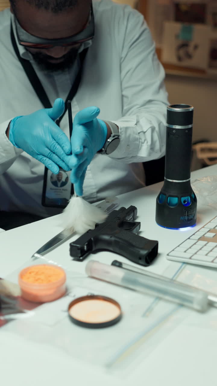Retsmediciner børster en pistol for fingeraftryk i et laboratorium