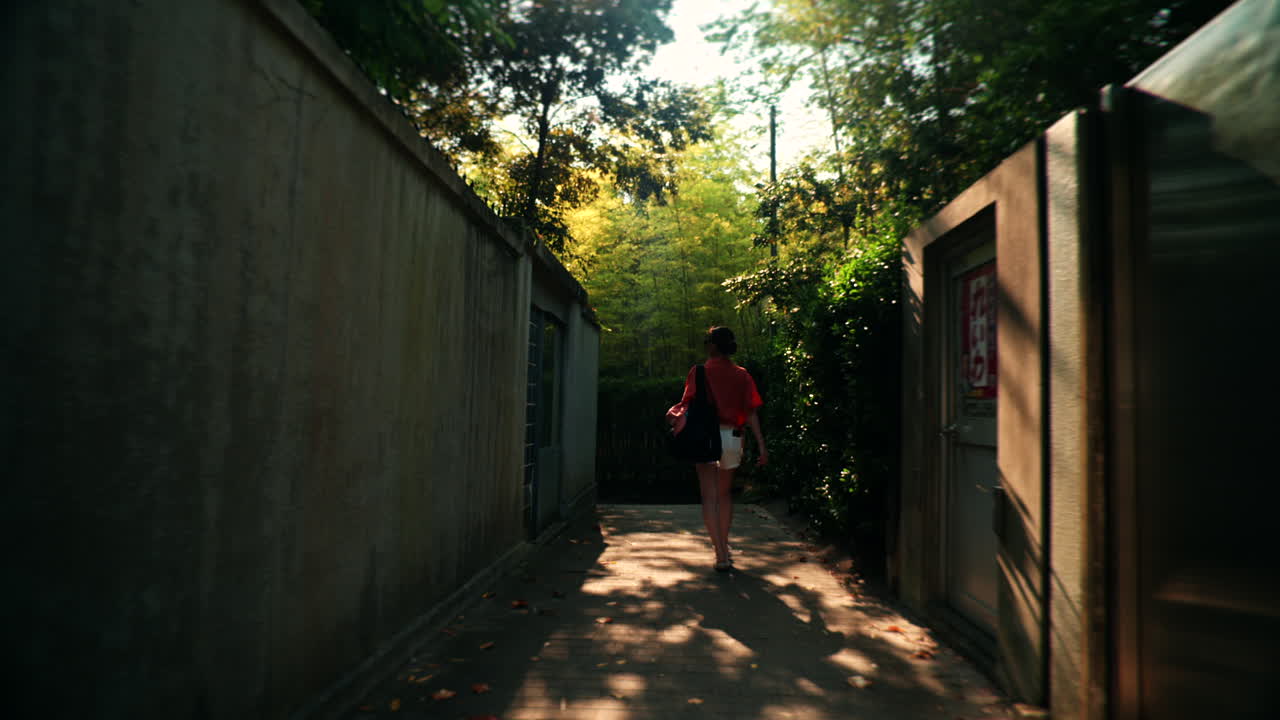 Woman Walking Down a Narrow Alley Lined with Trees