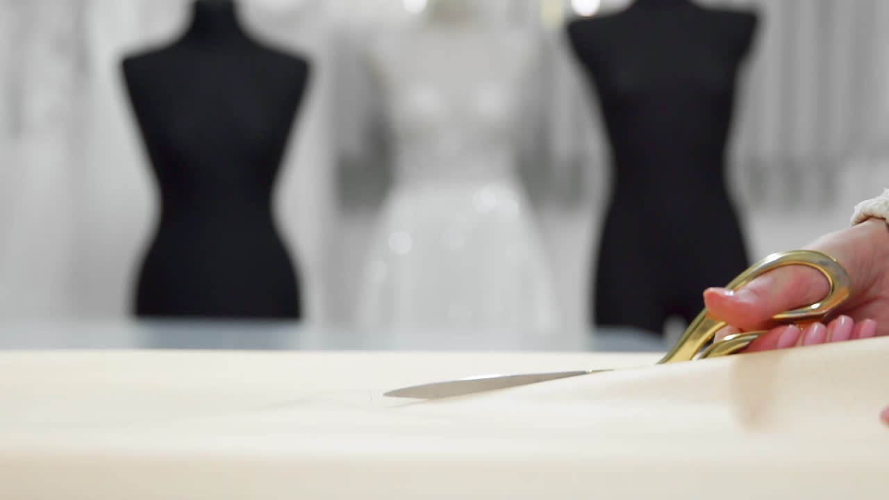 아름다운 패션 디자이너 소녀는 웨딩 드레스를 입은 인형 배경에 천을 위해 금 가위 패턴으로 종이에 잘라. 웨딩 드레스의 제조업체.