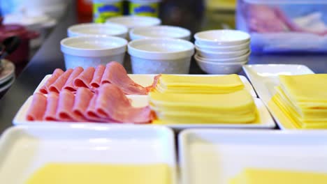 person preparing a breakfast, serving ham and cheese