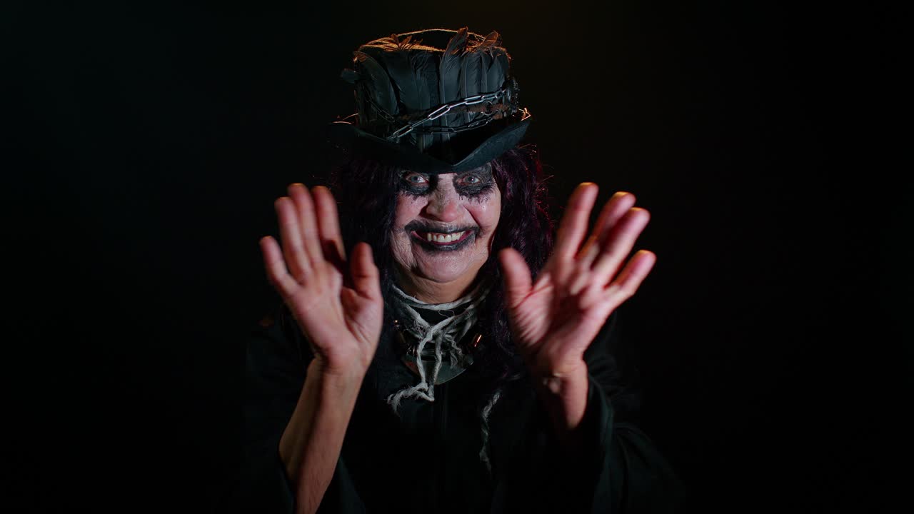 mujer mayor aterradora con maquillaje de bruja de halloween agita la palma de la mano en hola hola gesto de bienvenida